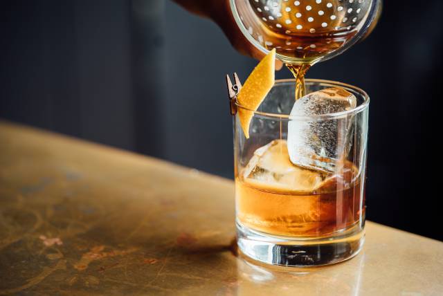 Cocktail mit Eiswürfel und Orangenschale
