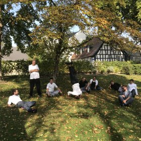 Küchenpersonal sitzt auf Rasen vor Landhotel Das Kronenschlösschen